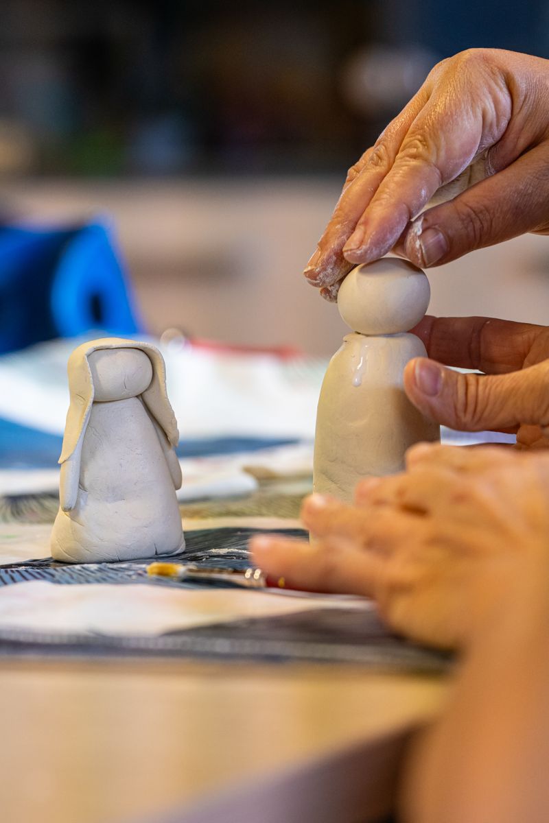 Mani al lavoro su piccole statuine in un laboratorio della Comunità